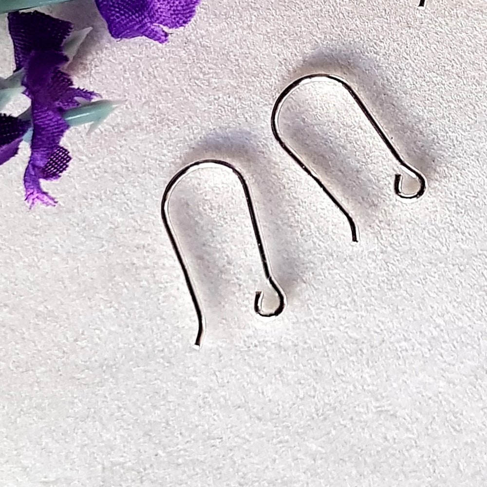 a pair of open kidney hooks on a white background purple flower in the top corner.