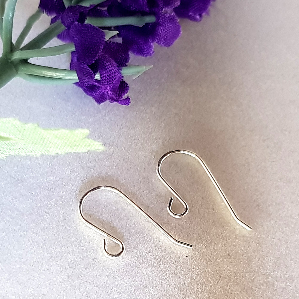 A pair of plain shepherd sterling silver earring hooks on a white background, purple flower top corner.