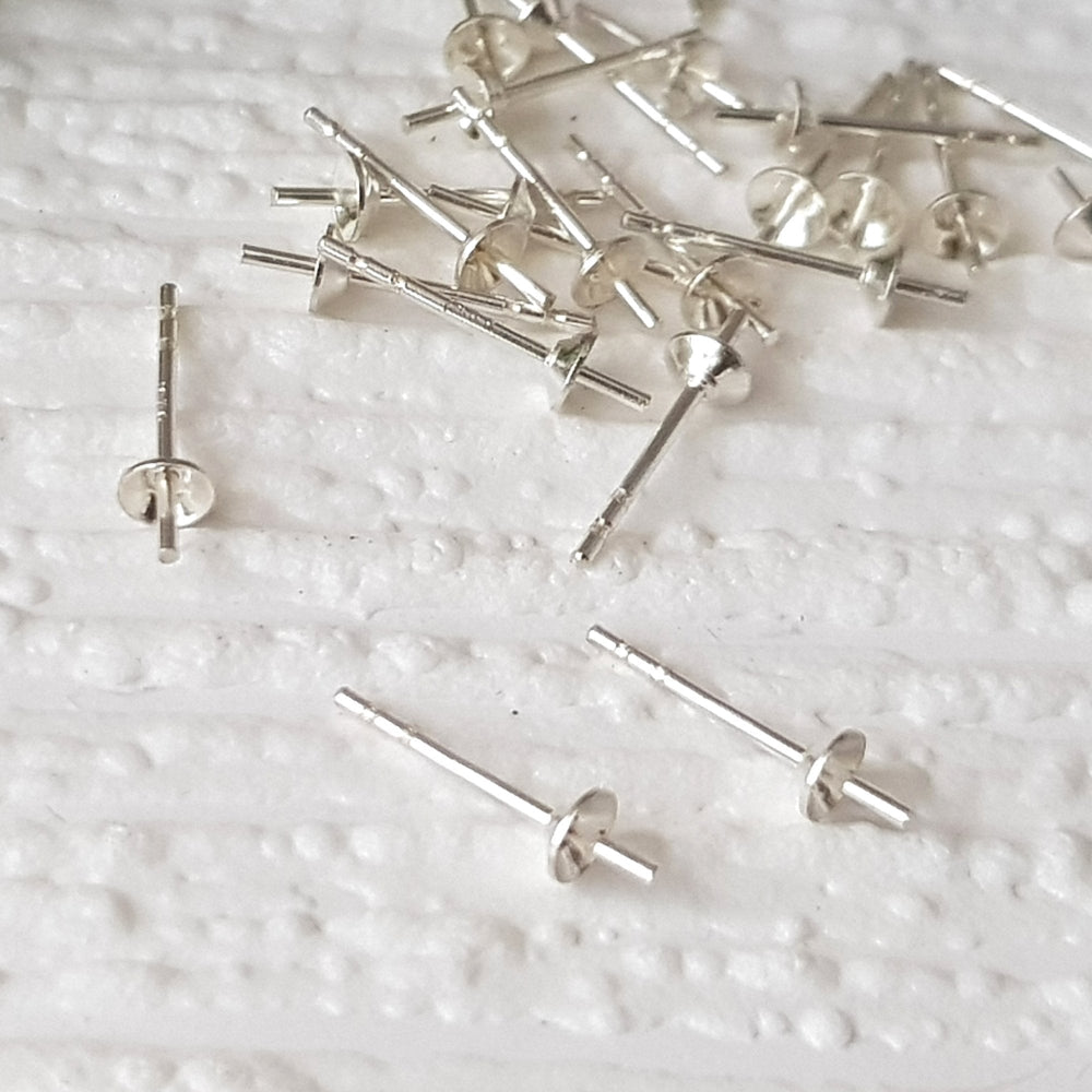 A bunch of fluted pearl cup studs on a white background