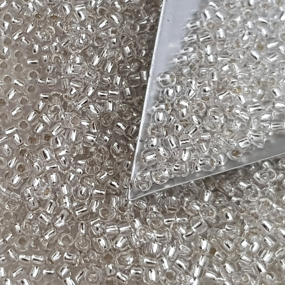8/0 Toho Seed Bead in crystal silver-lined with a triangle scoop.