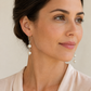 Model wearing handmade pearl drop earrings with sterling silver kidney hooks against a neutral background – FKJ-209E by Kalitheo