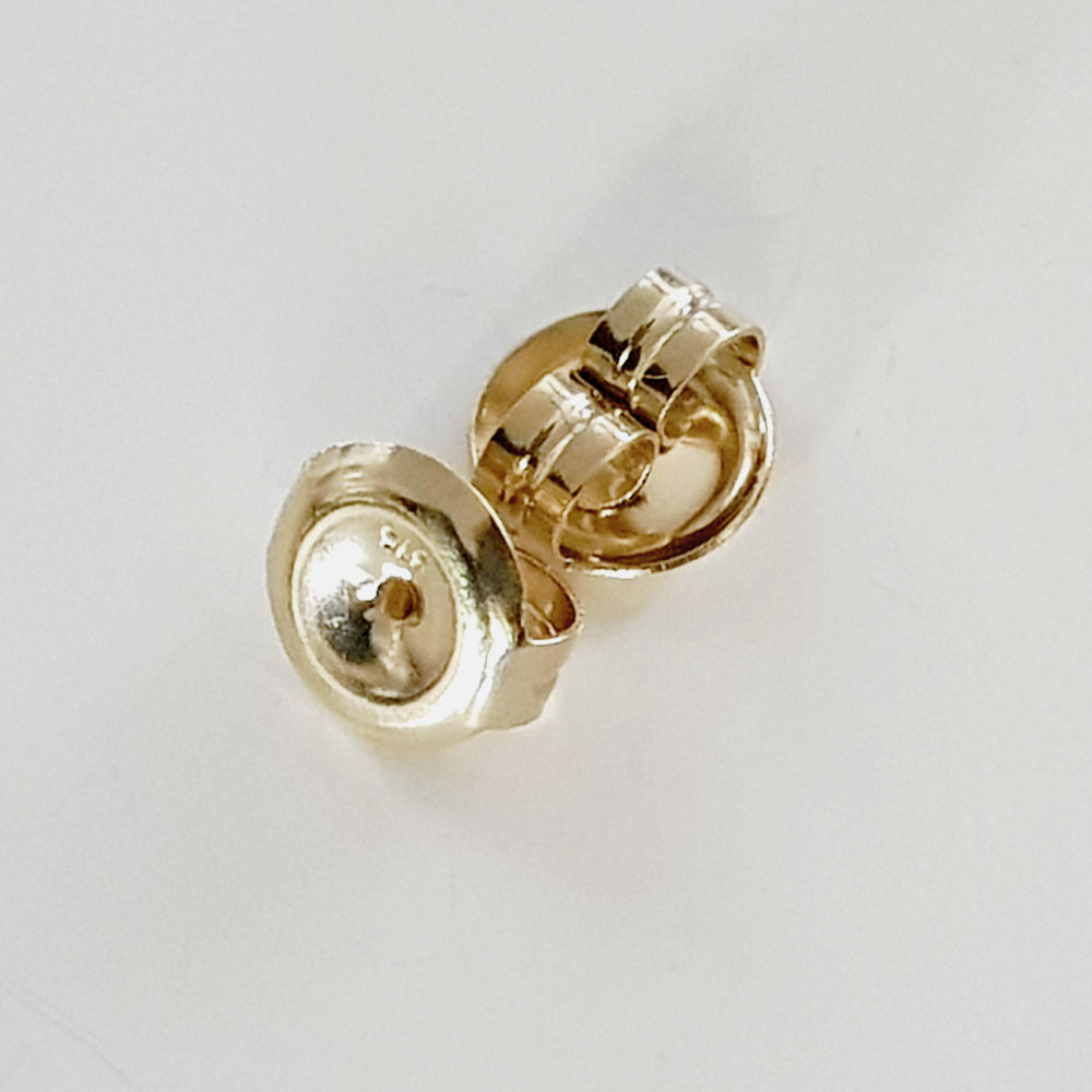Yellow Gold Earring backs on white background.
