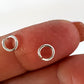 Two silver open jump rings on a person's finger against a white background