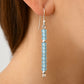 Light blue beaded earrings on a person's ear with a neutral background