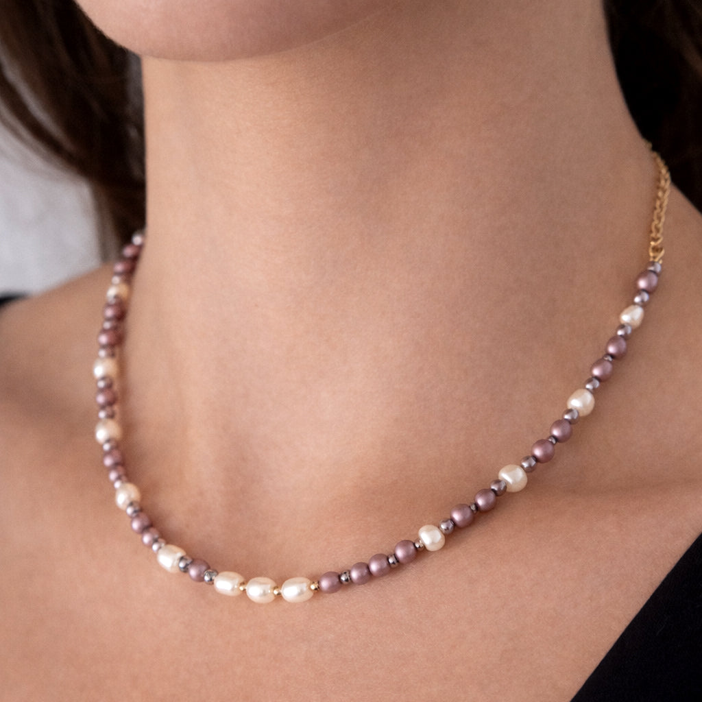 Pearl necklace worn by a person on a neutral background