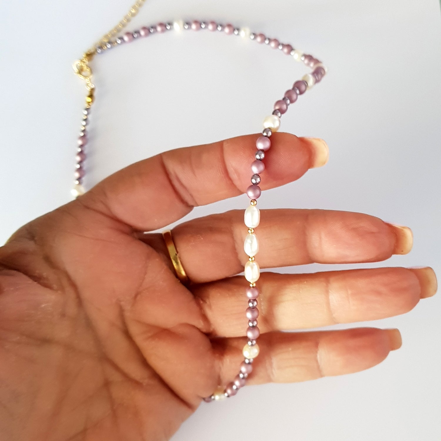 Hand holding a pearl necklace against a white background