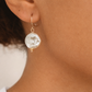 Close-up of a person wearing a gold earring with a baroque Pearl.