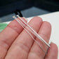 A pair of flat head headpins made of sterling silver, held in a person's fingers, with a blurred background.