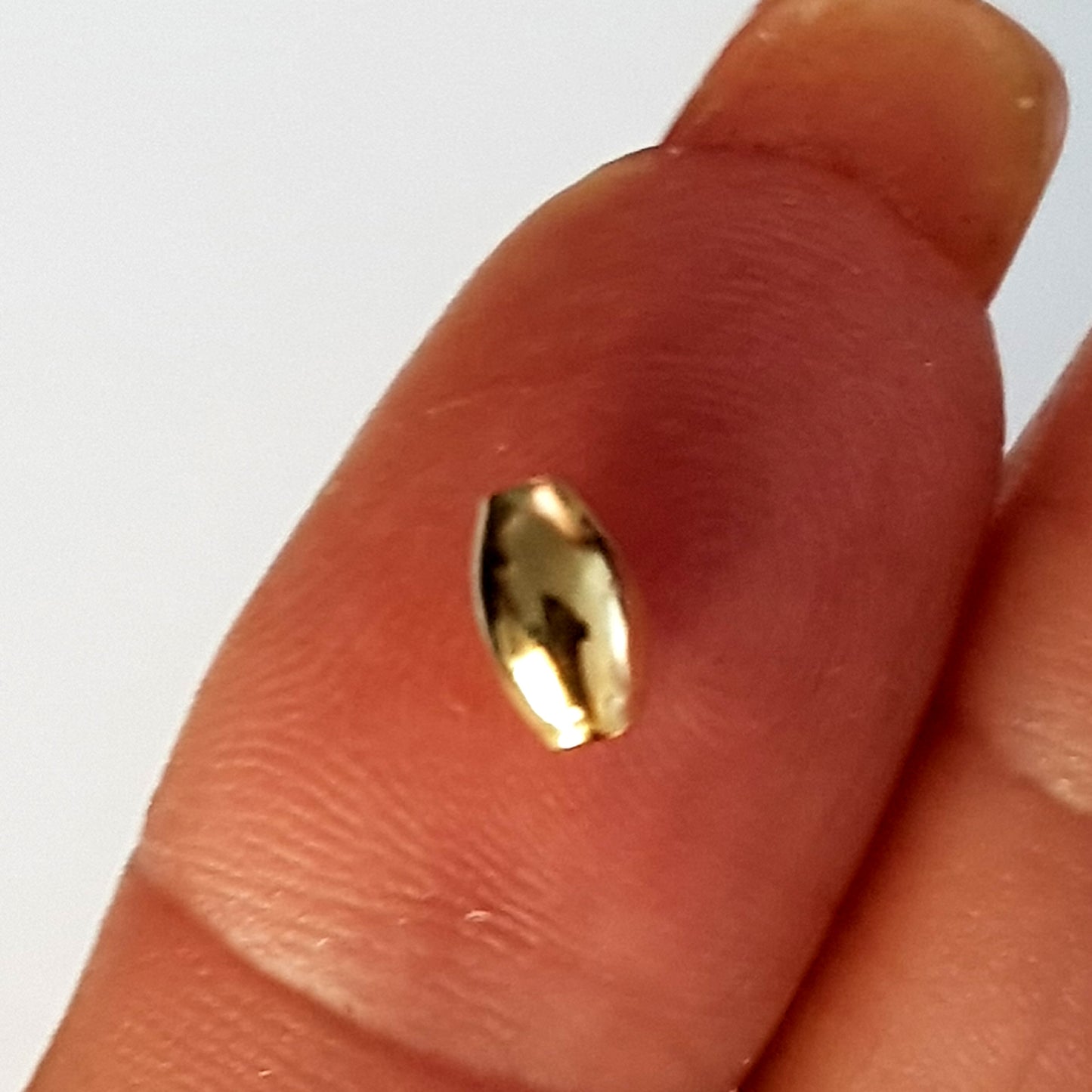 Gold bead on a finger against a white background