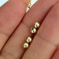 Three gold round beads on a hand against a light background