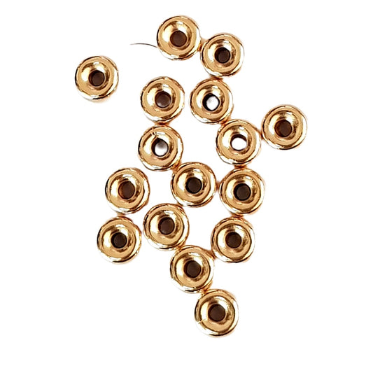 Gold rondel beads with indented  centers on a white background