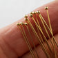 Gold headpins on a hand on a white background