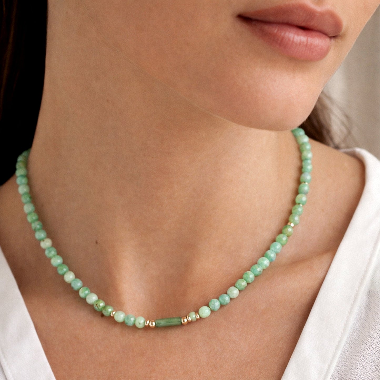 Green beaded Jade necklace worn by a person with a white shirt