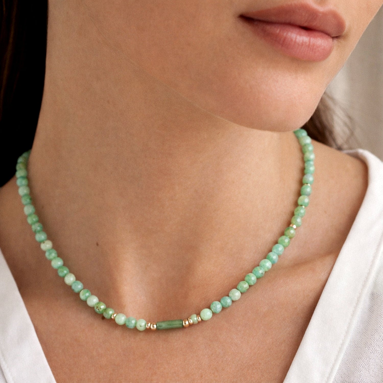 Green beaded Jade necklace worn by a person with a white shirt