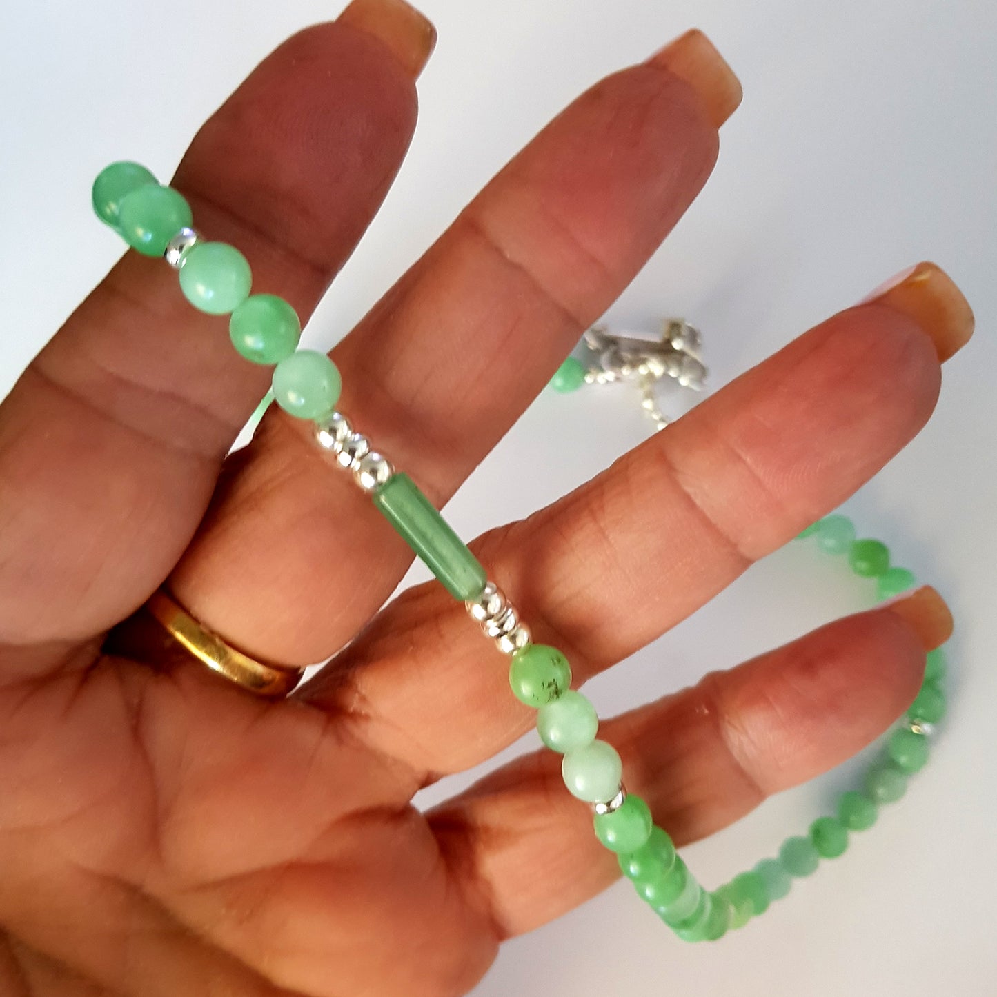 Green beaded bracelet on a hand with a plain background
