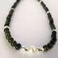 Necklace with green beads and a pearl-like pendant on a white background