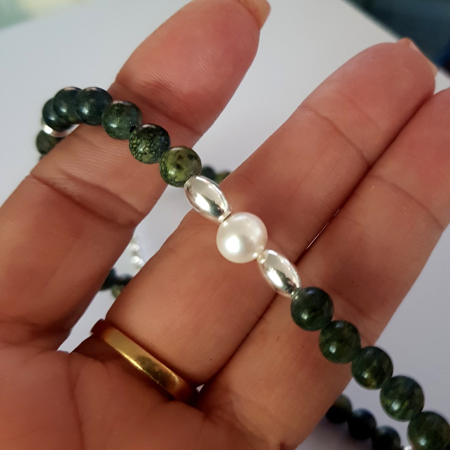 Hand holding necklace with pearl focal
