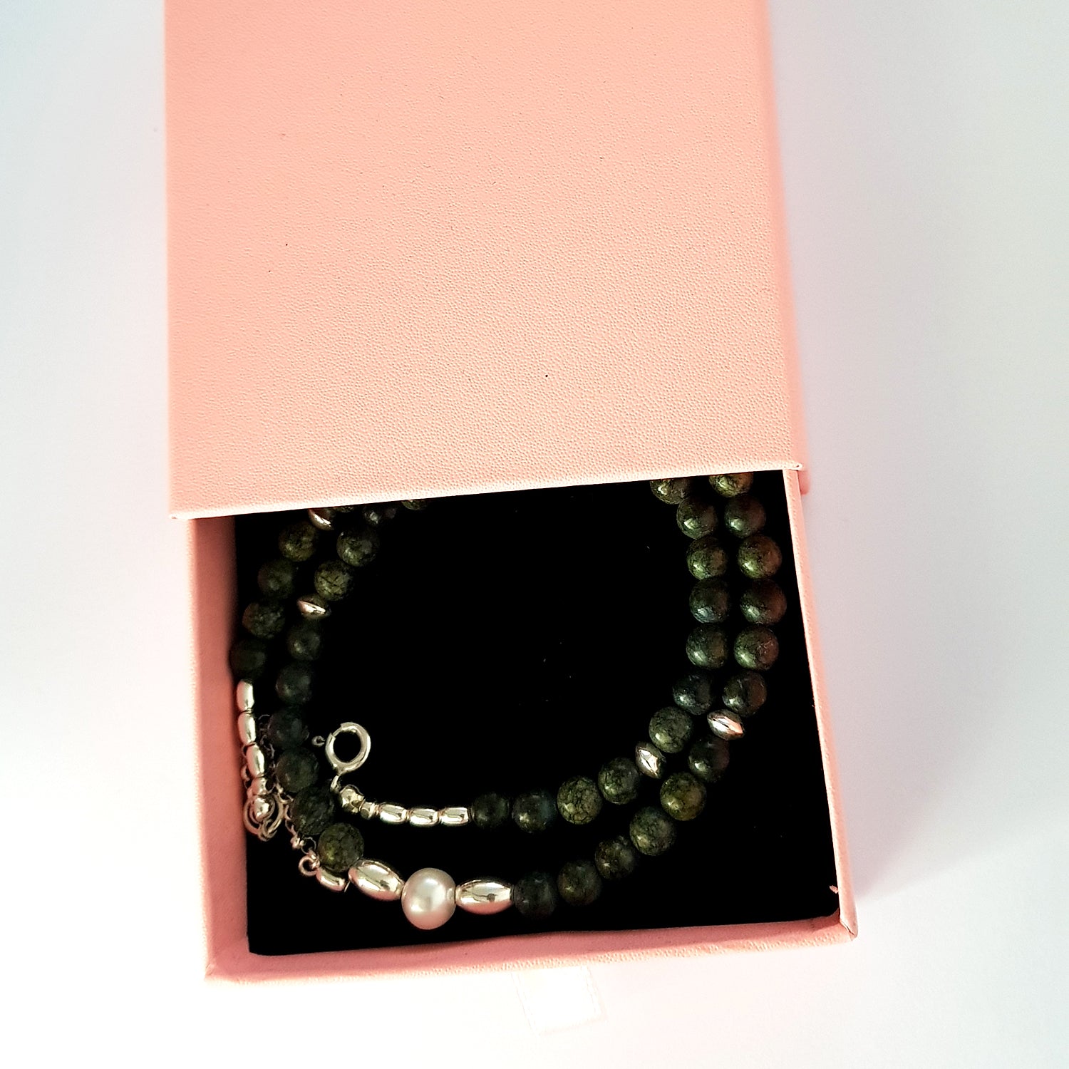 A beaded Necklace in a pink box on a white background