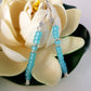 Turquoise beaded earrings on a white flower background