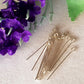 silver eye pins laying on a white background with purple flowers on one side.