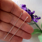 two sterling silver eye pins on a human hand, blurred background