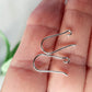 A per of open kidney hooks on a persons hand blurred background