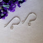 silver earring hooks on their side white background purple flower top corner.