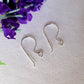 A pair of earring hooks laying on white background purple flower top corner.
