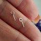Two soldered closed eye-pins made of sterling silver, displayed on a person's hand.