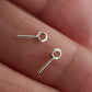 Two soldered closed eye-pins made of sterling silver, displayed on a person's hand.