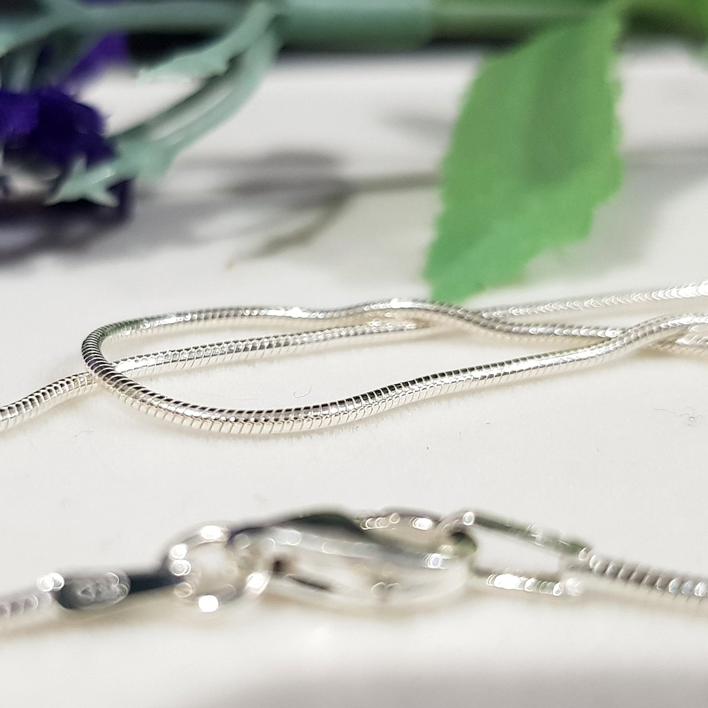 Sterling Silver Finished Snake Chain laying down  close up white background