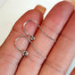 Silver earrings with small gemstones held between fingers on a neutral background