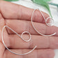 A pair of handmade large earring hooks on a hand with blurred background.