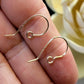 Gold earring hooks on a hand with a blurred background