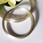 Two coiled pieces of 1.0mm round Argentium Silver 940 wire, placed on a white surface with a flower in the background.