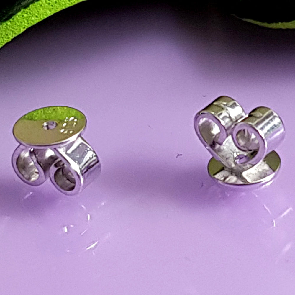 White Gold Disc Butterfly Earring Backs on a pink background.