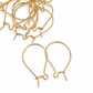 Bulk lot of gold filled kidney ear hooks scattered on white background with two hooks in foreground showing front detail