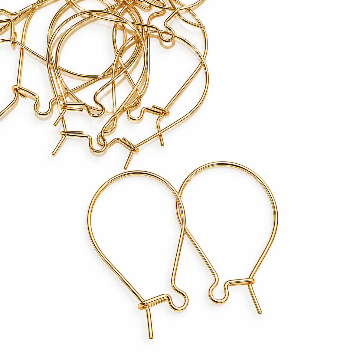 Bulk lot of gold filled kidney ear hooks scattered on white background with two hooks in foreground showing front detail