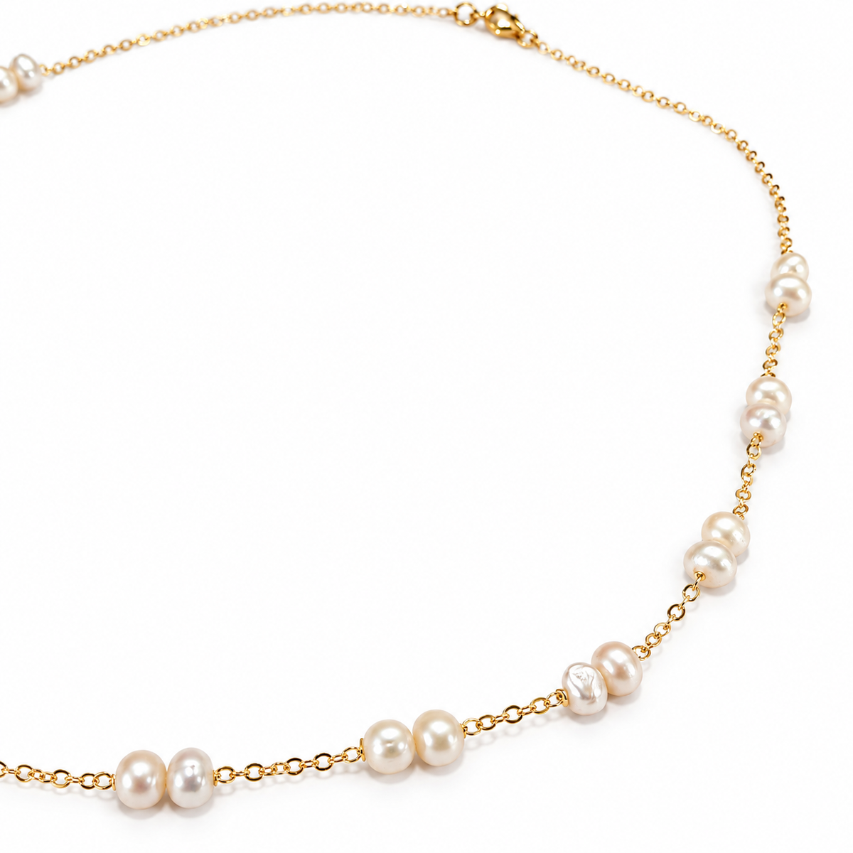 Detail shot of clustered and single freshwater pearls spaced along gold filled chain necklace, showing natural pearl variation