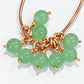 Loose pairs of handmade 6.5 mm green jade bead drop dangles with open jump rings on a white background