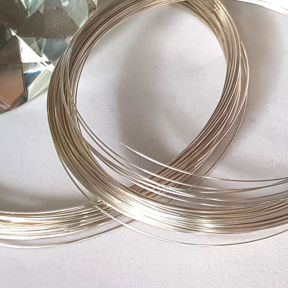 Coiled sterling silver wire on a light background, used for jewelry making.