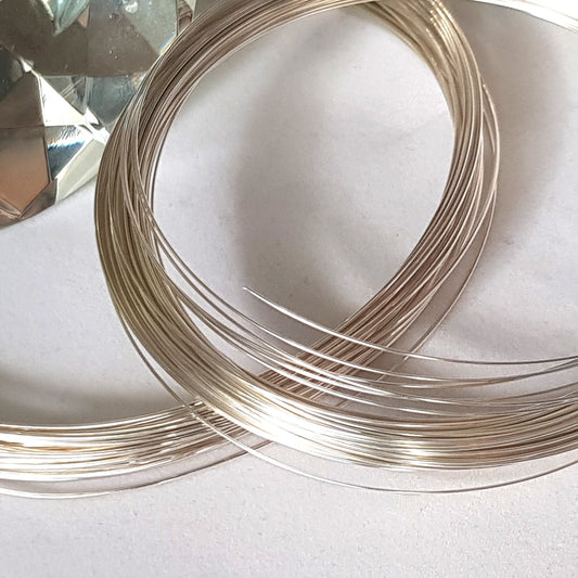 Coiled sterling silver wire on a light background, used for jewelry making.