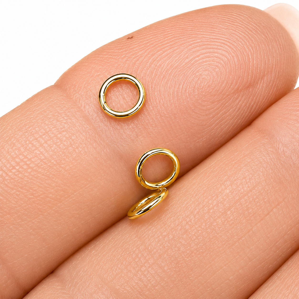 Sterling Silver Gold Plated Closed Jump Rings 5mm x 0.8mm for jewellery making and jewellery repairs. on a hand.