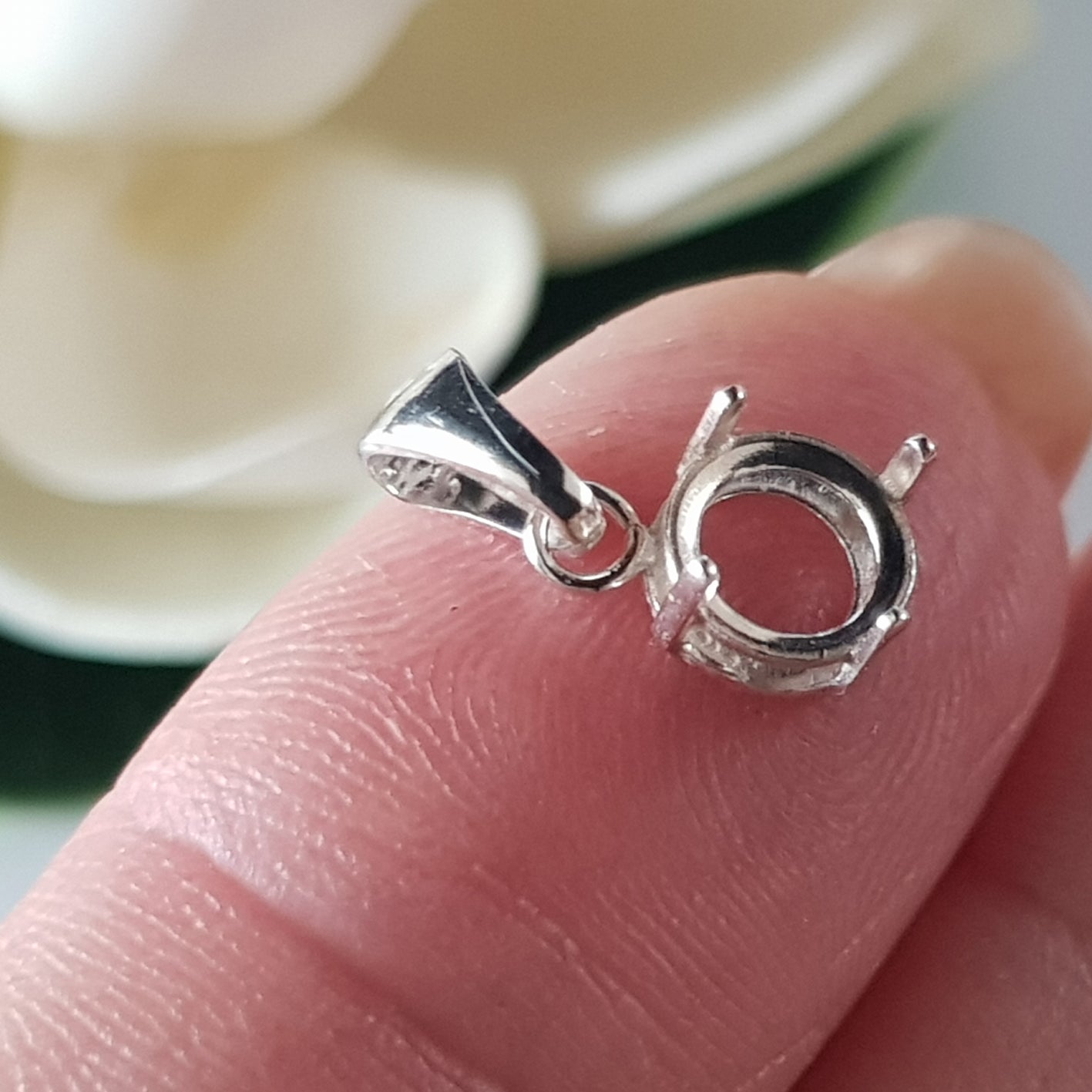 sterling silver 925 basket claw setting on a finger blurred background