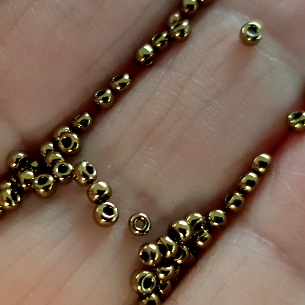 close up antique bronze beads on a hand.