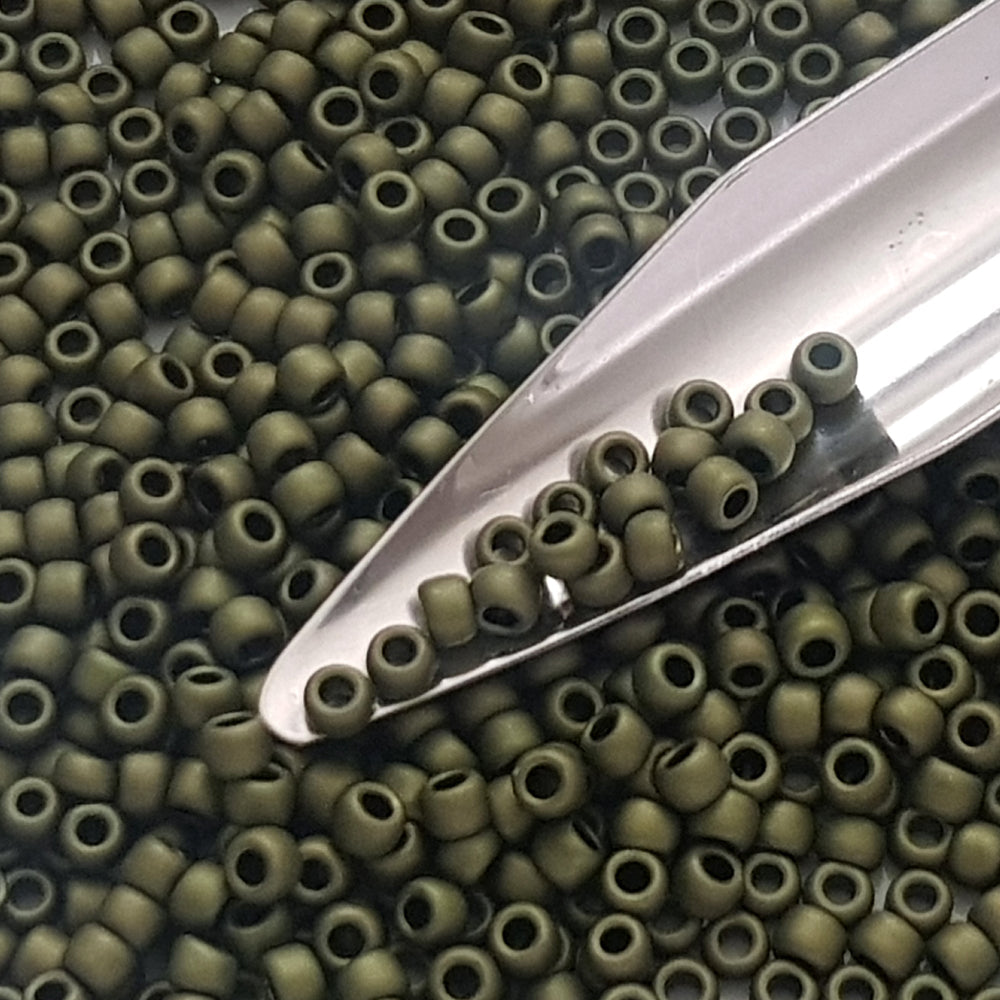 close up dark olive matte beads with a beading scoop.