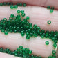 11/0 Toho Seed Beads in grass green transparent TR-7B between fingers.