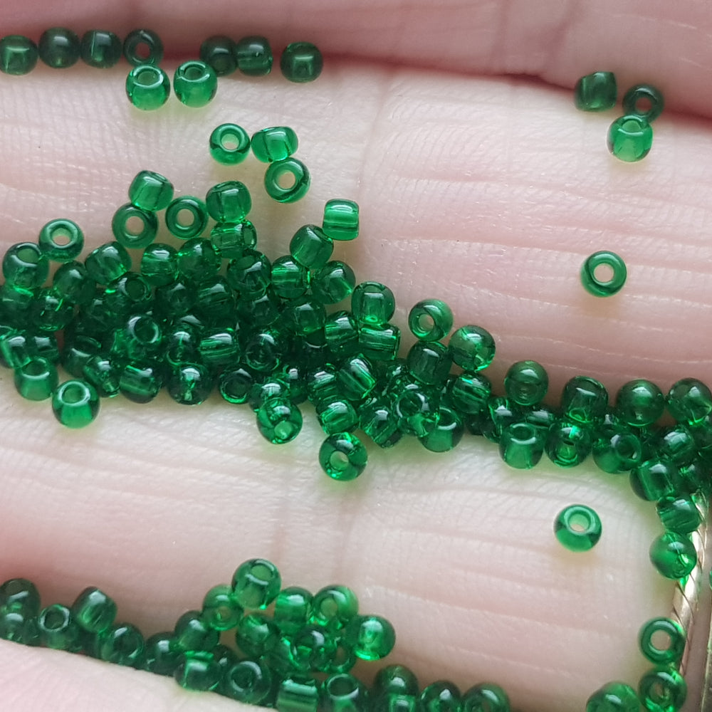 11/0 Toho Seed Beads in grass green transparent TR-7B between fingers.