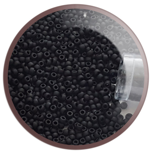 A clear plastic container filled with round jet black frosted opaque Toho seed beads, 15/0, 