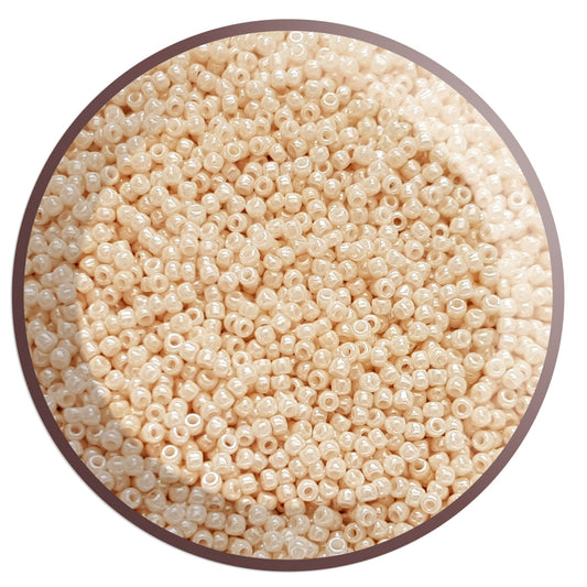 A close-up view of light beige opaque luster round Toho seed beads.